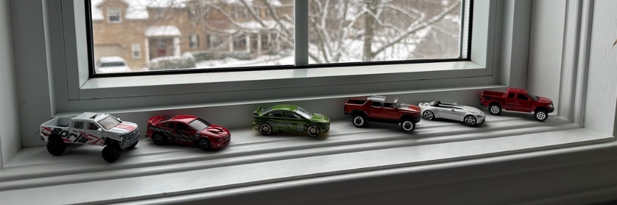 tiny toy cars lined up on a windowsill